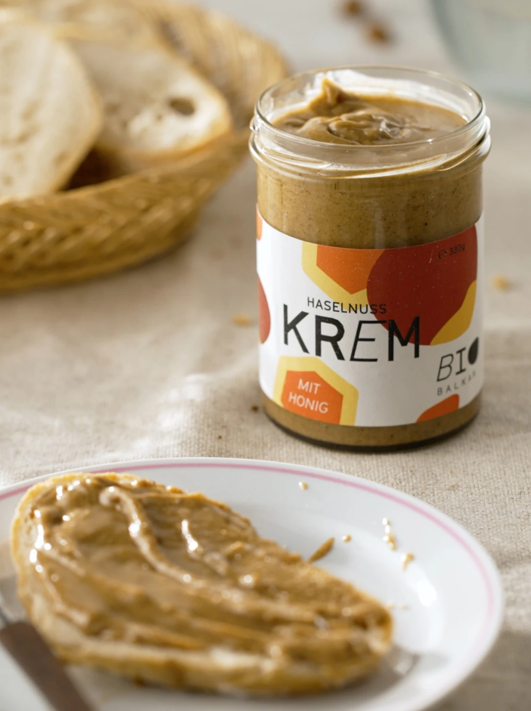 Brot, gestrichen mit Bio Krem mit Honig, auf gedecktem Frühstückstisch